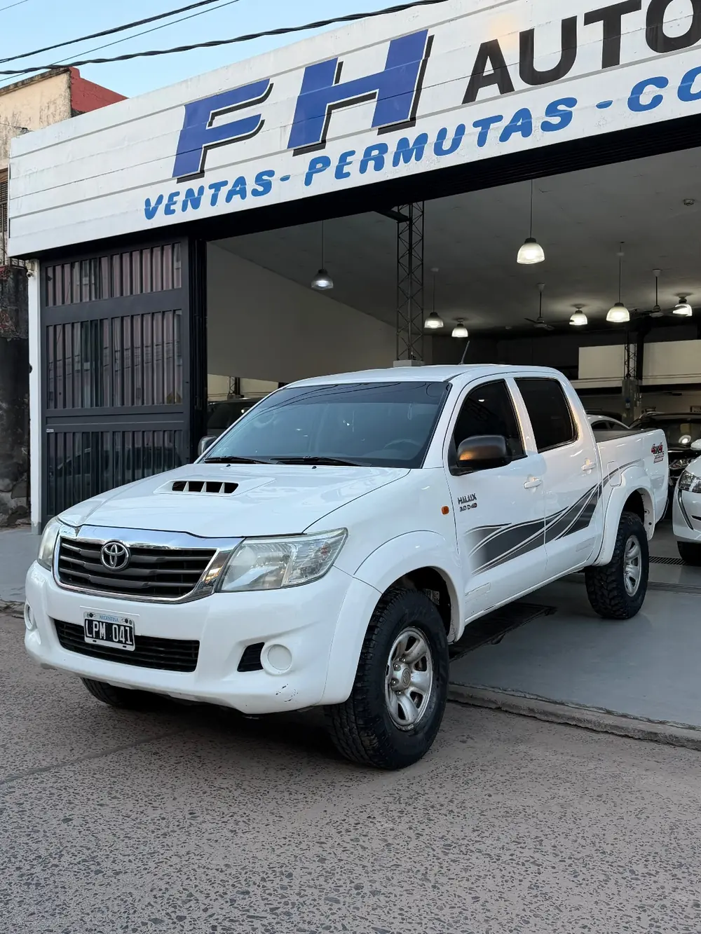 Toyota Hilux SR 2012 frente al cartel de FH Automotores